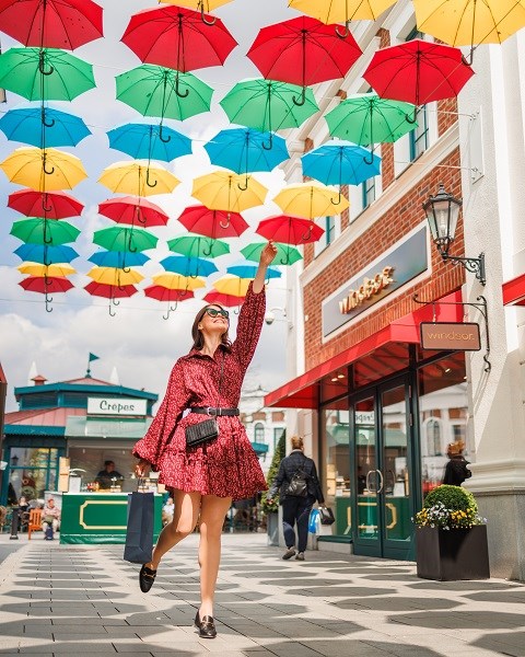En kvinde under farverige paraplyer i Designer Outlet Neumünster.
