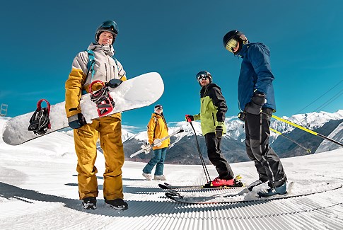 Fire skiløbere i sneen på en solskinsdag