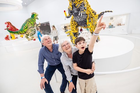 Bedsteforældre kigger på LEGO® dinosaurer sammen med deres barnebarn i LEGO® House