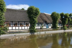 Stråtækt hus i Nordby på Samsø, der spejler sig i søen