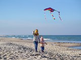 To små børn flyver med en drage på stranden en efterårsdag