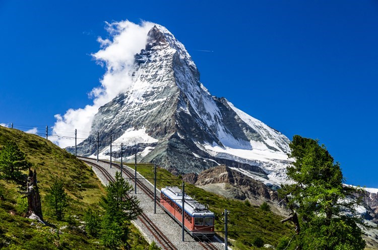 Et tog kører forbi en bjergtop i Schweiz
