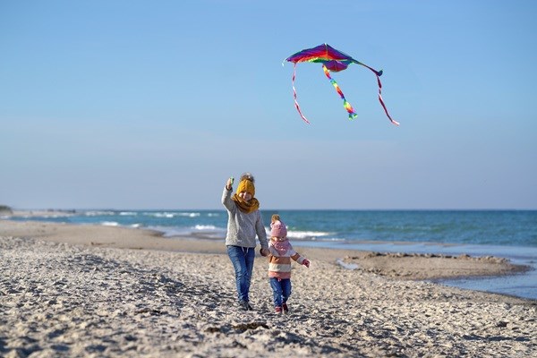 To små børn flyver med en drage på stranden en efterårsdag