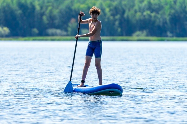 En teenagedreng står på paddleboard 