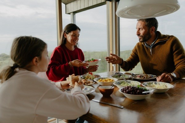 En familie på tre sidder og spiser aftensmad i et dansk sommerhus