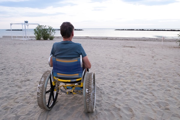 En mand i en strandkørestol på stranden 