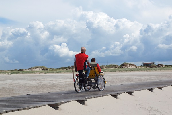 To mænd på en kørestols-ladcykel på vej til stranden 