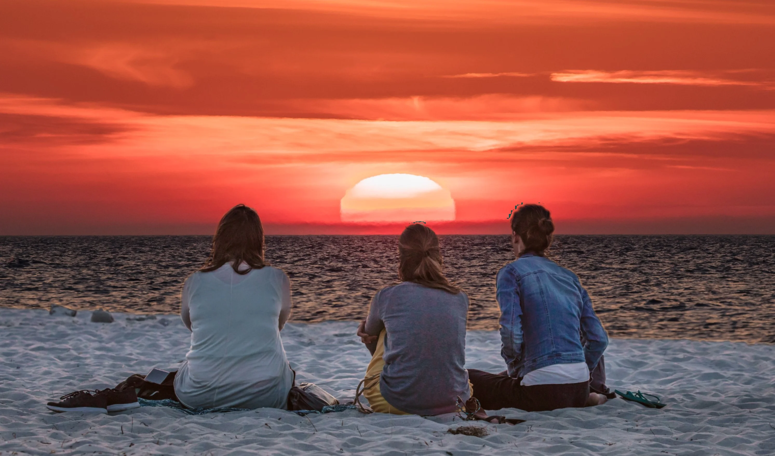 Tre veninder nyder solnedgangen på stranden