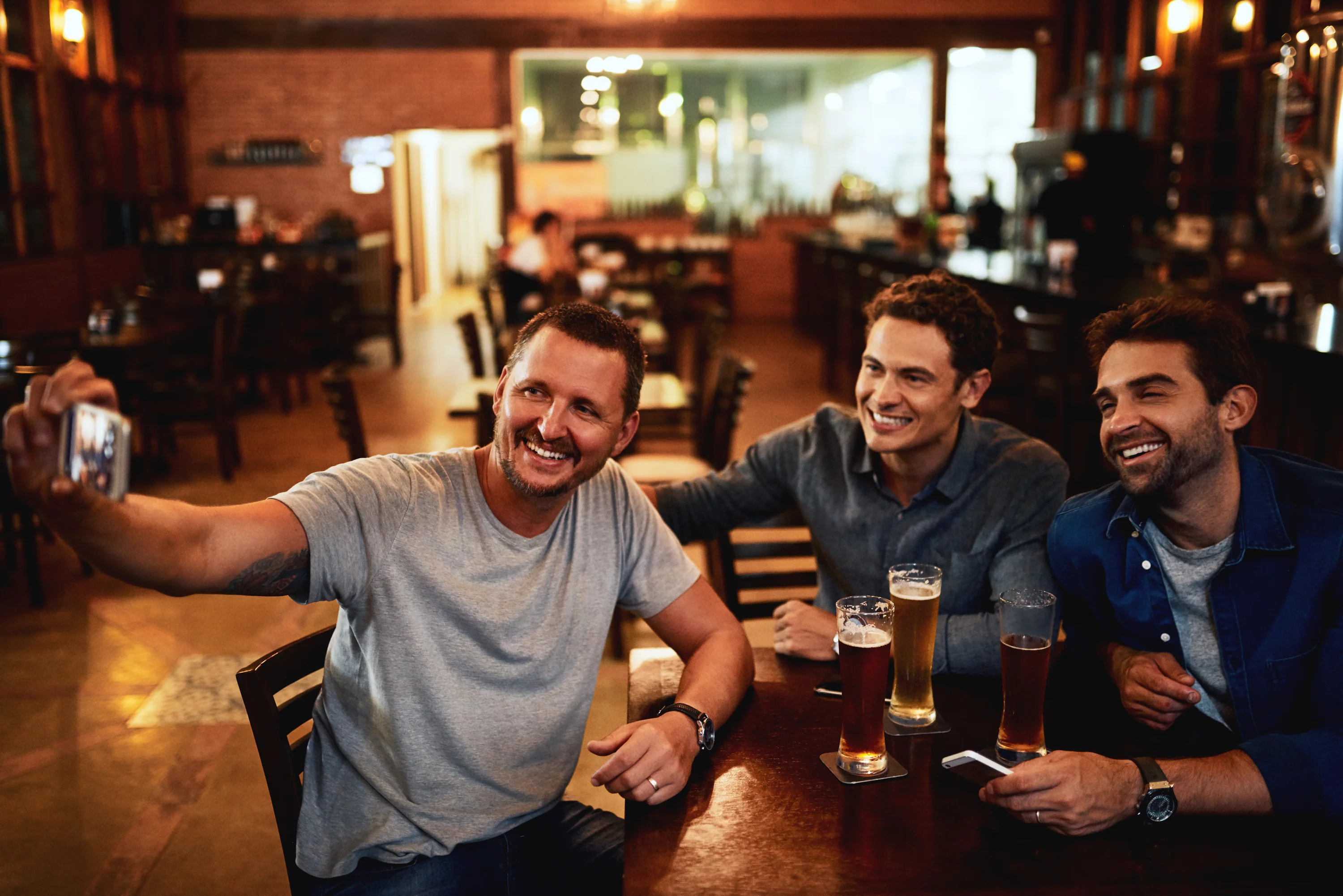 Tre mænd drikker øl på en bar
