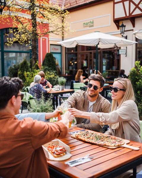 To par skåler og spiser pizza i Designer Outlet Neumünster