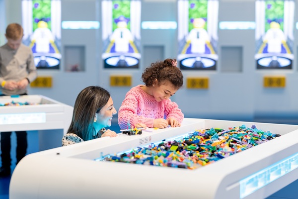 En lille pige bygger med LEGO® klodser sammen med sin mor i LEGO® House