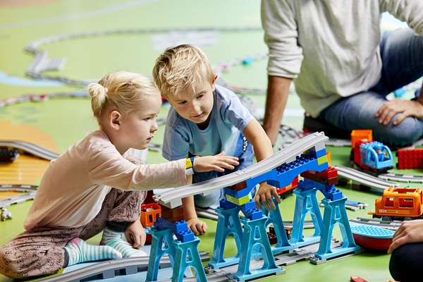 En dreng og en pige leger med et DUPLO® tog i LEGO® House
